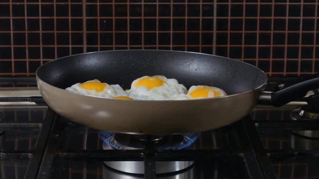 Woman shakes scrumbled eggs on the frying pan