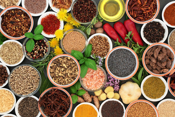 Fresh and dried herbs and spices in bowls and loose forming a colourful abstract background. Top view.