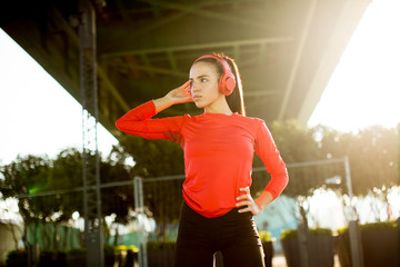 Young attractive female  runner taking break after jogging outdoors
