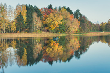 Farewell to Autumn as the final leaf-fall has begun. Sunny October day at Āraiši lake with stunning mirror reflections in water. 