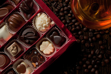 box of Belgian chocolate pralines surrounded by coffee beans and a cognac glass romantic atmosphere