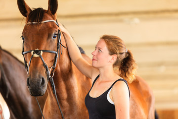 Obraz premium Jockey young girl petting and hugging brown horse