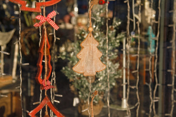 Wooden toy christmas tree hanging in storefront window decorating for New Year and Christmas