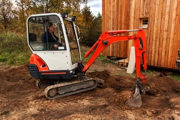 Mini excavator on construction site. Excavator regulates the terrain around the house.