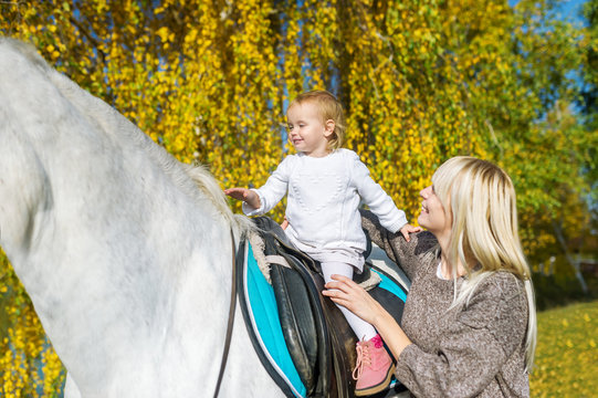 A Beautiful Mother Outdoors With Horse And Baby Daughter Horseback