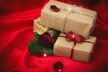 gifts wrapped in wrapping paper with a red rose on red fabric