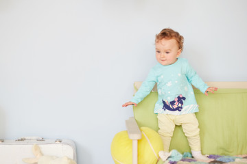 Little baby playing on at home. A small baby girl is left alone in her room