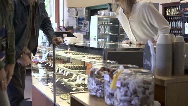 Medium shot of a couple choosing cake in a pastry shop