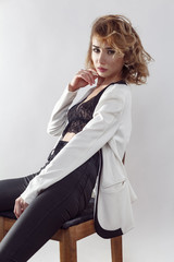 Beautiful young sexy fashion model posing in bra and undressing her white jaket and looking at camera with passion.