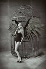 blond woman with black wings in a cage. Angel, mysticism