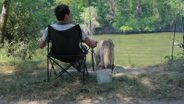 man fishing in river with siberian husky. Man with dog resting and having fun on fishing