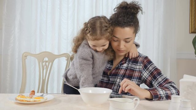 Woman and girl embrace each other during breakfast