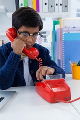 Boy imitating as businessman using land line phone - obrazy, fototapety, plakaty