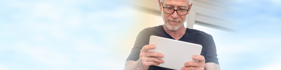 Mature man using digital tablet, light effect