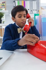 Boy pretending as businessman talking on land line phone - obrazy, fototapety, plakaty