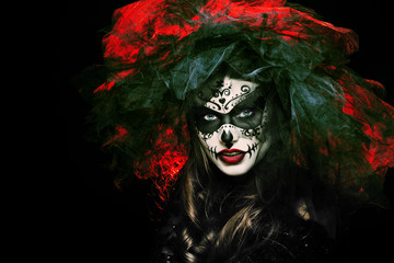 Close up studio portrait of beautiful woman with Halloween sugar skull makeup in red and black colors, wearing bridal veil. Model looking at camera. Dark bride. Copy, empty space for text. 