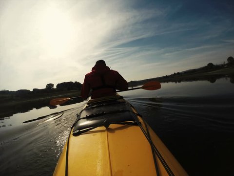 Time lapse of kayaker paddling canoe at sunset