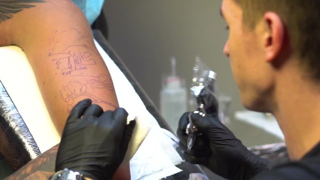 Tattoo master starts to work on the tattoo according sketch