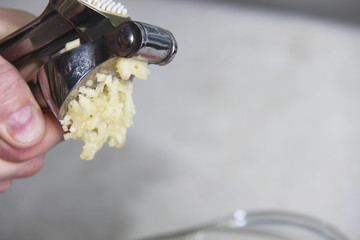 Caucasian male hand holding a garlic masher.