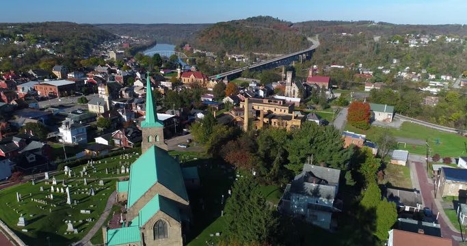 A morning high angle forward aerial establishing shot of the small town of Brownsville, PA - a Pittsburgh suburb. Bridges over the Monongahela River in the distance.	 	
