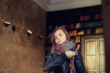 Fototapeta premium Close up shot of beautiful mixed race young brunette woman looking at the mirror touching hair leaving modern cafe dressing up by the exit. Attractive female student dressed in authentic scarf indoor