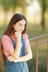 Brooding long-haired beautiful teenage girl is thinking about something sad