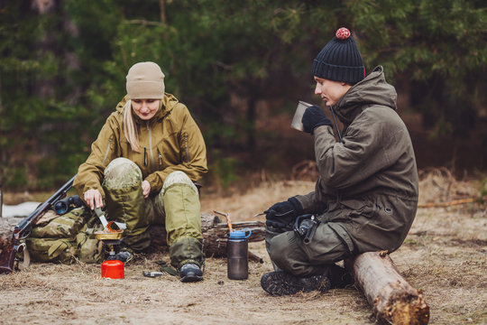 Two hunters are eating together in the forest. Bushcraft, hunting and people concept