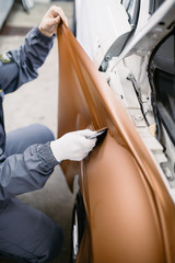 Car wrapping specialist putting vinyl foil or film on car.