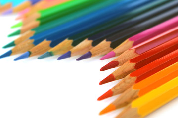 Multicolor bright color pencils diagonal wave on white background with red pencil on focus