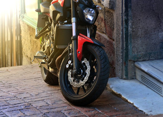 The motorcycle is parked in the street at the entrance to the old building