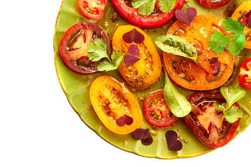 Green plate of salad with sliced tomatoes on white