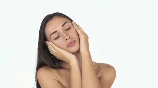 Tender young woman toucher her face with palms and enjoys it posing for camera