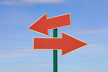 Road sign with two red arrows over blue sky