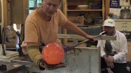 Medium shot of a man blowing glass in a workshop
