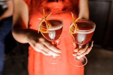 Woman in red dress holding three glasses with fresh cocktails