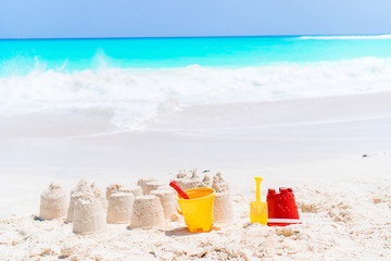 Sandcastle at white beach with plastic kids toys and sea background
