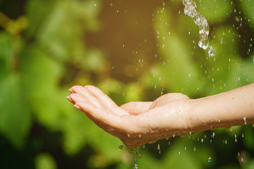 Side view of woman washing hand outdoors. Natural drinking water in the palm. Young hands with water splash, selective focus. Instagram