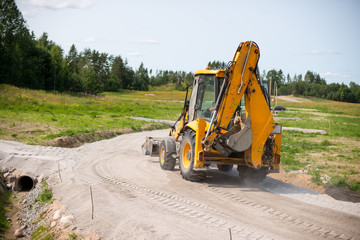 Yellow excavator rides in the workplace © Vladimir