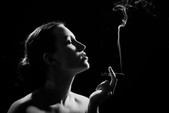 luxury woman smoking cigarette on black background, monochrome