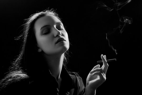 beautiful woman smoking cigarette on black background, monochrome