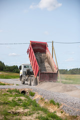 Obraz premium Dump truck is unloading soil. Dumper truck is unloading soil or sand at construction site