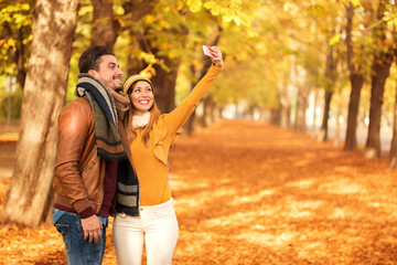 Beautiful couple taking a selfie at a park in autumn