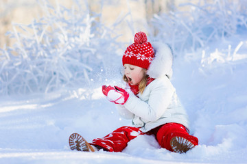 Child playing with snow in winter. Kids outdoors.