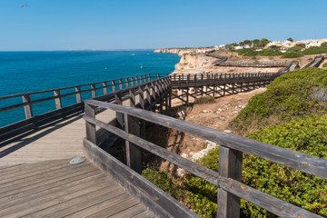 Obraz premium Wooden walkway to beautiful Carvoeiro beach with cliff and rock formation Algarve region Portugal
