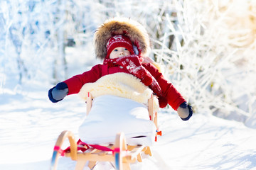 Sled and snow fun for kids. Baby sledding in winter park.