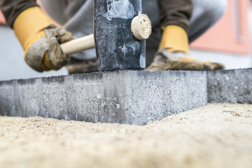 Builder tamping down a new paving slab or brick