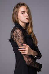 Young brunette lady in black dress posing on grey background