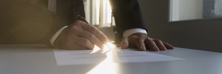 Panorama view of businessman in a shadowy office signing contract
