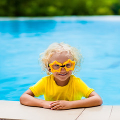 Naklejka premium Child with goggles in swimming pool. Kids swim.