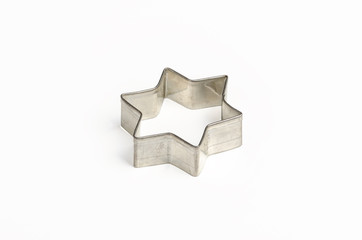 Star shaped Christmas cookie cutter over white. Tin biscuit cutter, a tool to cut cookie dough in...